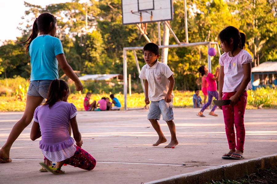 Grupo de niños y niñas jugando pelota en algún lugar de la selva peruana.