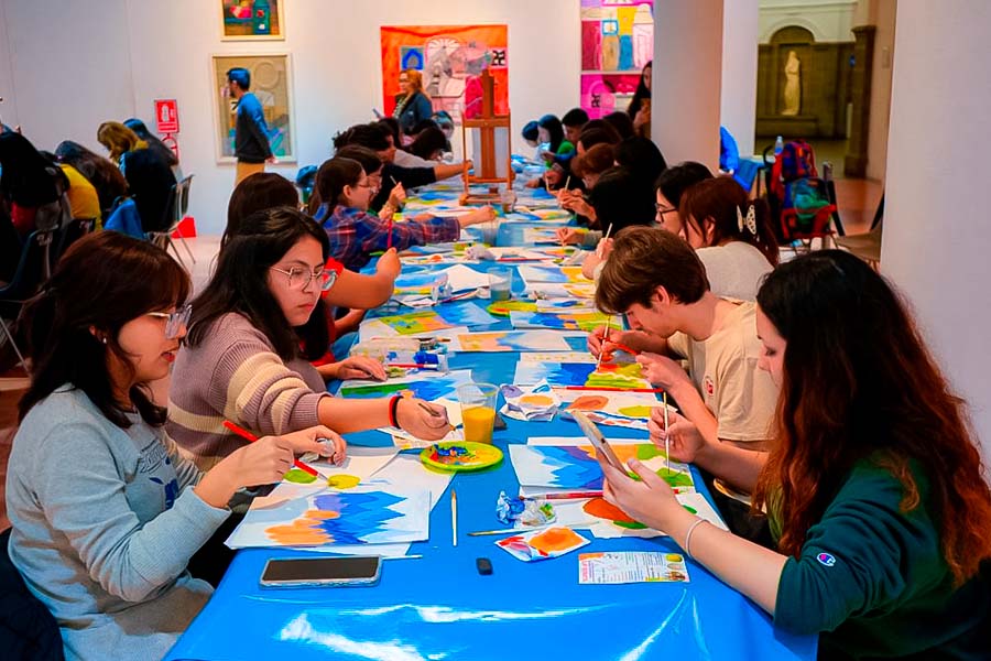 Grupo de jóvenes sentados en una mesa, en un taller de pintura y arte.