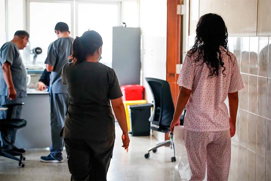 Una médico y una paciente paradas en el pasillo de un hospital.