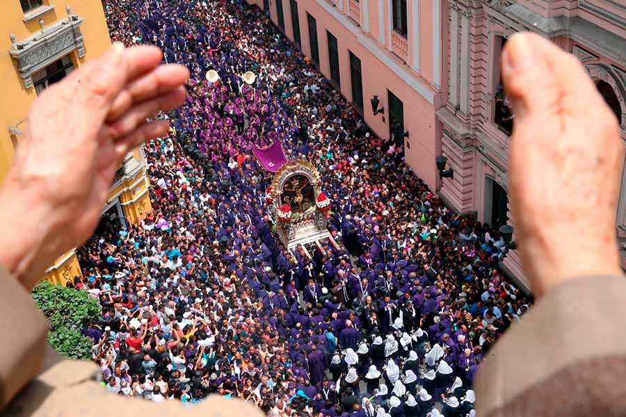 La procesion del Señor de los Milagros vista desde arriba, entre unas manos que lo alaban.