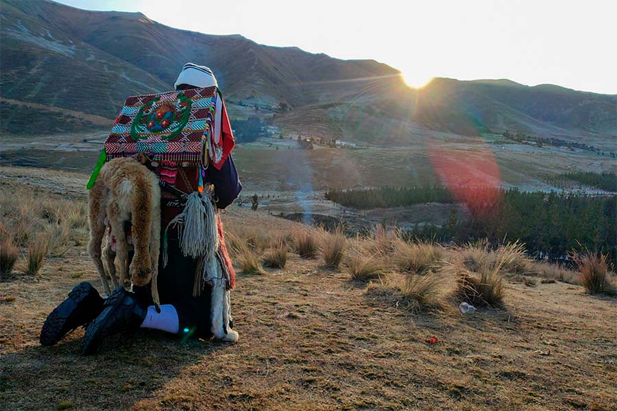 Un peregrino con traje típico rezando en la montaña en Cusco.