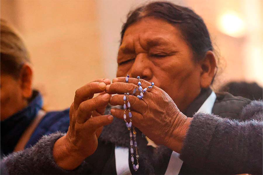 Señora rezando el rosario en una iglesia.